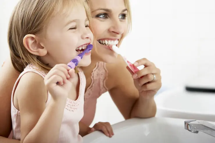 Mutter und Tochter putzen gemeinsam Zähne
