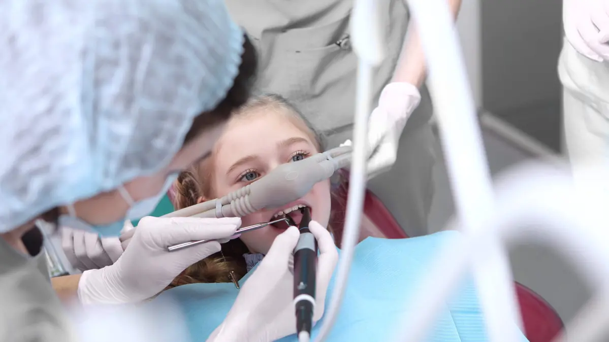 Junge Patientin mit Lachgas-Maske während einer Zahnbehandlung